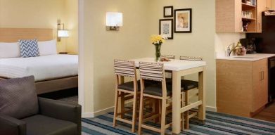 Double bed guest room in Sonesta ES Suites Atlanta - Perimeter Center North, furnished with dining table and four tall stools, with an armchair nearby.