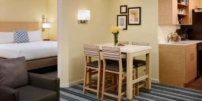 Double bed guest room in Sonesta ES Suites Atlanta - Perimeter Center North, furnished with dining table and four tall stools, with an armchair nearby.