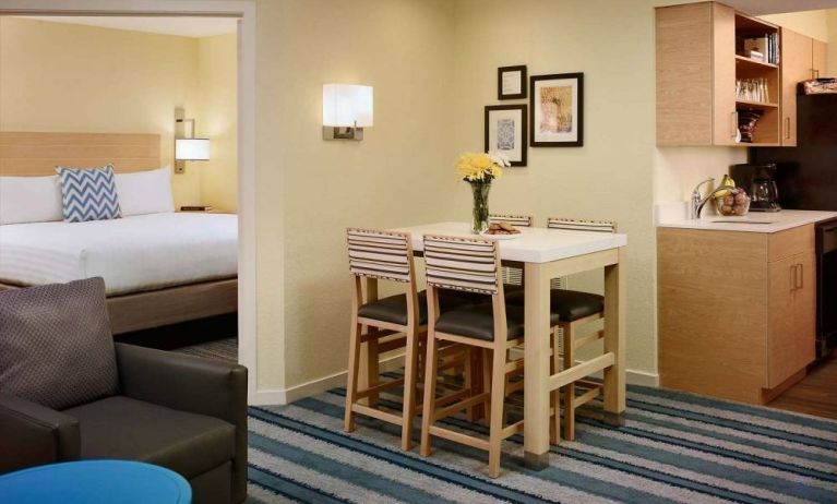 Double bed guest room in Sonesta ES Suites Atlanta - Perimeter Center North, furnished with dining table and four tall stools, with an armchair nearby.