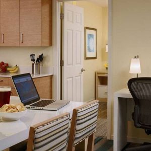 Guest room workspace in Sonesta ES Suites Atlanta - Perimeter Center North, featuring desk, chair, and lamp, next to the kitchen area.