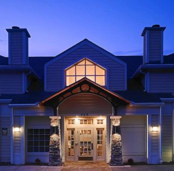 The hotel’s exterior has an entrance roof supported by rustic stonework pillars, with small trees on either side.