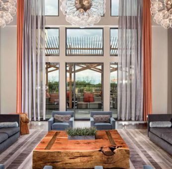 Sonesta Bee Cave Austin’s lobby lounge is furnished with armchair and sofa seating amid an airy setting, with the patio just steps away.