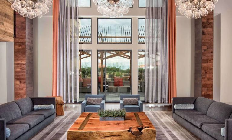 Sonesta Bee Cave Austin’s lobby lounge is furnished with armchair and sofa seating amid an airy setting, with the patio just steps away.