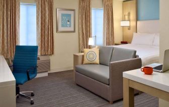 Sonesta ES Suites Auburn Hills Detroit double bed guest room, featuring table, chairs, windows, and a sofa.