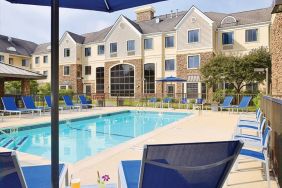 Sonesta ES Suites Auburn Hills Detroit’s outdoor pool has sun loungers, chairs, and small tables around it, with shade available.