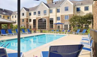 Sonesta ES Suites Auburn Hills Detroit’s outdoor pool has sun loungers, chairs, and small tables around it, with shade available.