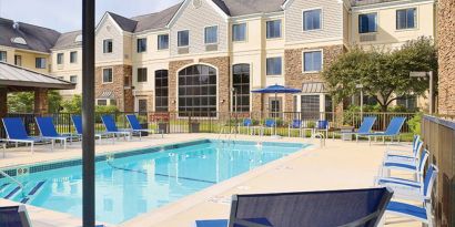 Sonesta ES Suites Auburn Hills Detroit’s outdoor pool has sun loungers, chairs, and small tables around it, with shade available.