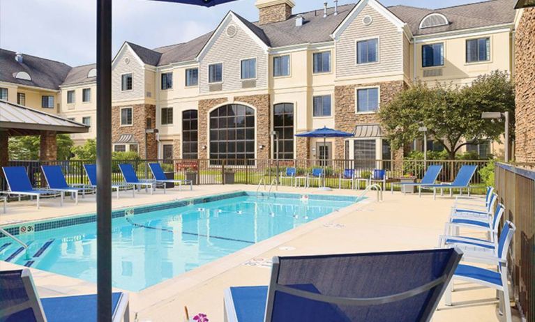 Sonesta ES Suites Auburn Hills Detroit’s outdoor pool has sun loungers, chairs, and small tables around it, with shade available.