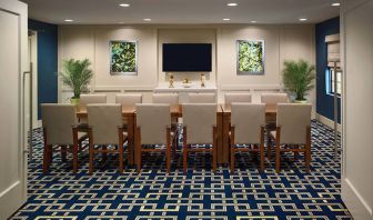 Sonesta ES Suites Auburn Hills Detroit meeting room, featuring a long table, a dozen chairs around it, and both art and a widescreen television on the wall.