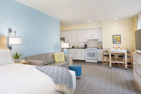 Double bed guest room in Sonesta ES Suites New Orleans, furnished with sofa and TV, plus kitchen area and dining table.