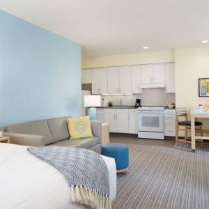 Double bed guest room in Sonesta ES Suites New Orleans, furnished with sofa and TV, plus kitchen area and dining table.