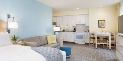 Double bed guest room in Sonesta ES Suites New Orleans, furnished with sofa and TV, plus kitchen area and dining table.