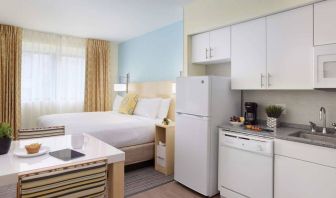 Sonesta ES Suites New Orleans double bed guest room, with nearby dining table and kitchen area, plus a large window.