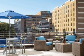 The rooftop terrace at Sonesta ES Suites New Orleans features armchairs and coffee tables, plus shaded tables and chairs, amid the fresh air.