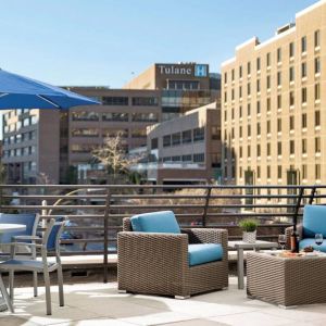 The rooftop terrace at Sonesta ES Suites New Orleans features armchairs and coffee tables, plus shaded tables and chairs, amid the fresh air.