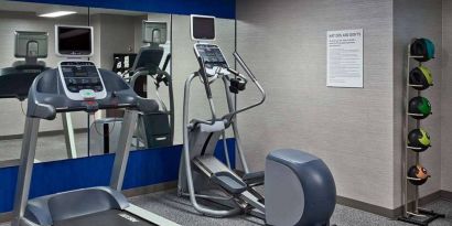 The hotel fitness center is equipped with towels, gym balls, and exercise machines such as an elliptical and a treadmill.