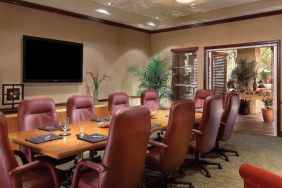 Meeting room in Sonesta Suites Scottsdale Gainey Ranch, furnished with long wooden table, 10 leather chairs, and a wall-mounted widescreen television.