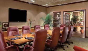 Meeting room in Sonesta Suites Scottsdale Gainey Ranch, furnished with long wooden table, 10 leather chairs, and a wall-mounted widescreen television.