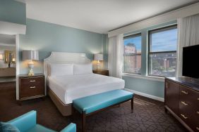 Double bed guest room in The Chase Park Plaza Royal Sonesta St. Louis, featuring armchair, windows, and TV.