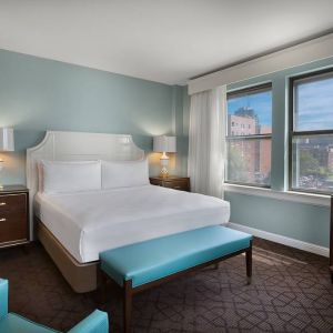 Double bed guest room in The Chase Park Plaza Royal Sonesta St. Louis, featuring armchair, windows, and TV.