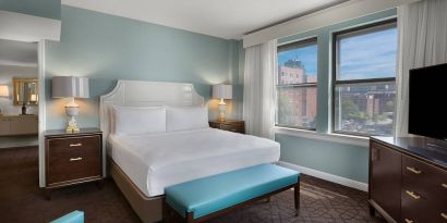 Double bed guest room in The Chase Park Plaza Royal Sonesta St. Louis, featuring armchair, windows, and TV.