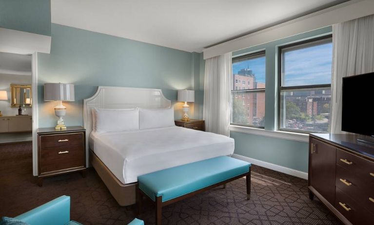 Double bed guest room in The Chase Park Plaza Royal Sonesta St. Louis, featuring armchair, windows, and TV.