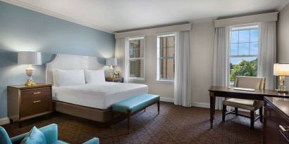 The Chase Park Plaza Royal Sonesta St. Louis double bed guest room, including armchair, workspace desk and chair, and windows.