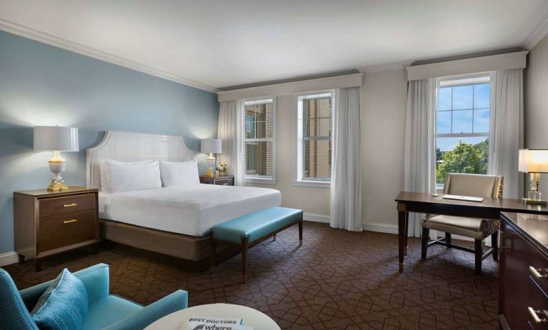 The Chase Park Plaza Royal Sonesta St. Louis double bed guest room, including armchair, workspace desk and chair, and windows.