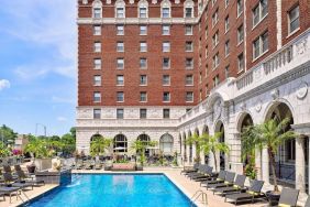 The Chase Park Plaza Royal Sonesta St. Louis’ outdoor pool has rows of sun loungers and potted palm trees by the side, plus sofa seating and a nearby patio.