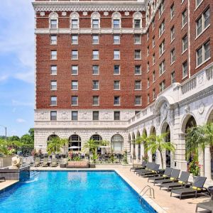 The Chase Park Plaza Royal Sonesta St. Louis’ outdoor pool has rows of sun loungers and potted palm trees by the side, plus sofa seating and a nearby patio.