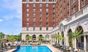 The Chase Park Plaza Royal Sonesta St. Louis’ outdoor pool has rows of sun loungers and potted palm trees by the side, plus sofa seating and a nearby patio.