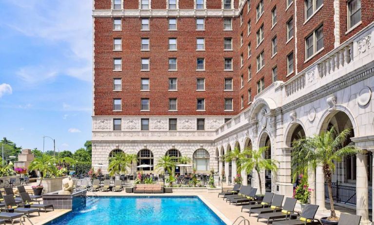 The Chase Park Plaza Royal Sonesta St. Louis’ outdoor pool has rows of sun loungers and potted palm trees by the side, plus sofa seating and a nearby patio.