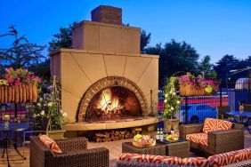 The outdoor fireplace at The Chase Park Plaza Royal Sonesta St. Louis has comfortable sofa and armchair seating nearby, in addition to coffee tables and beautiful flowers.