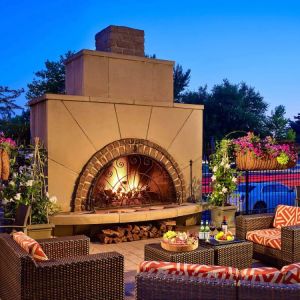 The outdoor fireplace at The Chase Park Plaza Royal Sonesta St. Louis has comfortable sofa and armchair seating nearby, in addition to coffee tables and beautiful flowers.