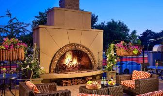 The outdoor fireplace at The Chase Park Plaza Royal Sonesta St. Louis has comfortable sofa and armchair seating nearby, in addition to coffee tables and beautiful flowers.