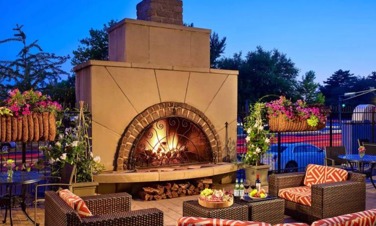 The outdoor fireplace at The Chase Park Plaza Royal Sonesta St. Louis has comfortable sofa and armchair seating nearby, in addition to coffee tables and beautiful flowers.