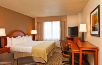 Double bed guest room in Sonesta Atlanta Airport South, featuring TV, window, and workspace desk and chair.