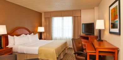 Double bed guest room in Sonesta Atlanta Airport South, featuring TV, window, and workspace desk and chair.