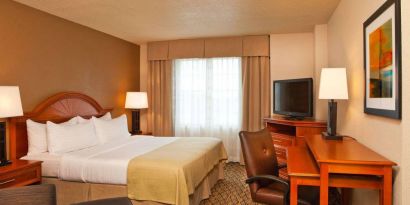 Double bed guest room in Sonesta Atlanta Airport South, featuring TV, window, and workspace desk and chair.