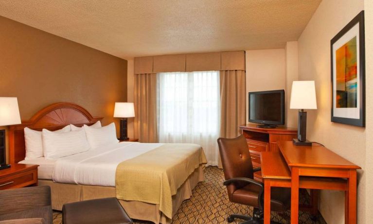 Double bed guest room in Sonesta Atlanta Airport South, featuring TV, window, and workspace desk and chair.