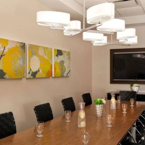 Sonesta Atlanta Airport South meeting room, furnished with long wooden table surrounded by swivel chairs, and art and a widescreen TV on the walls.