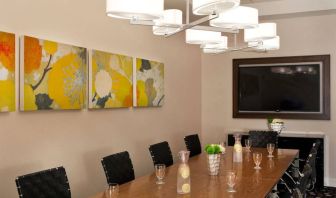 Sonesta Atlanta Airport South meeting room, furnished with long wooden table surrounded by swivel chairs, and art and a widescreen TV on the walls.