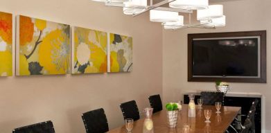 Sonesta Atlanta Airport South meeting room, furnished with long wooden table surrounded by swivel chairs, and art and a widescreen TV on the walls.