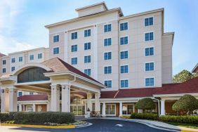 Sonesta Atlanta Airport South’s exterior features a covered entrance, well-kept greenery, and stylish red roof tiles.