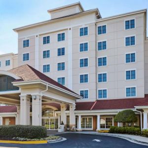 Sonesta Atlanta Airport South’s exterior features a covered entrance, well-kept greenery, and stylish red roof tiles.