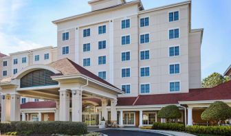 Sonesta Atlanta Airport South’s exterior features a covered entrance, well-kept greenery, and stylish red roof tiles.