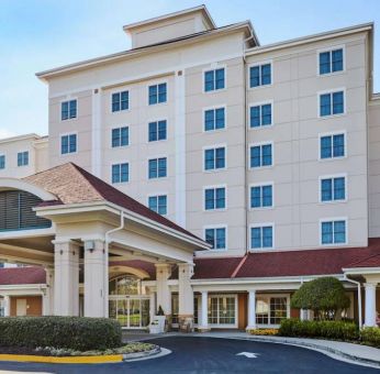 Sonesta Atlanta Airport South’s exterior features a covered entrance, well-kept greenery, and stylish red roof tiles.