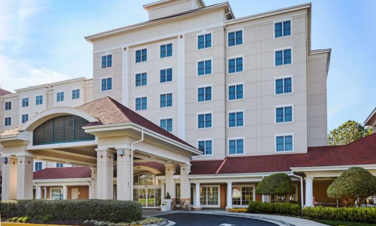 Sonesta Atlanta Airport South’s exterior features a covered entrance, well-kept greenery, and stylish red roof tiles.