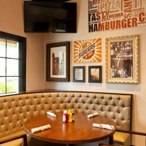 The Burger Place is Sonesta Atlanta Airport South’s on-site restaurant, and includes burger-related art on the wall alongside a widescreen TV, and large windows.