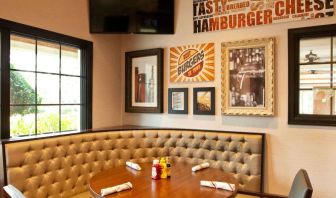 The Burger Place is Sonesta Atlanta Airport South’s on-site restaurant, and includes burger-related art on the wall alongside a widescreen TV, and large windows.